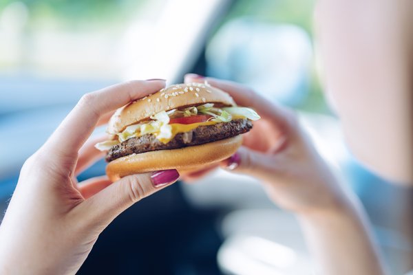 Hands holding up a fast food burger.