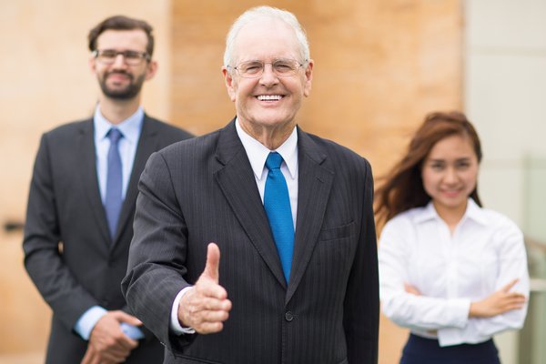 Man extends hand for handshake with colleagues nearby