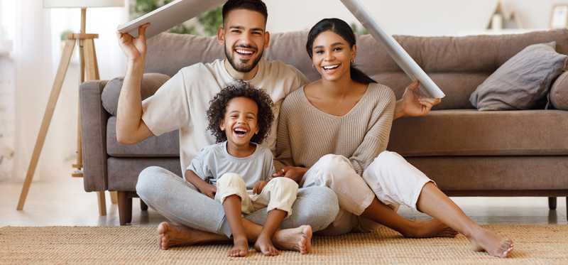 Two adults and a child under a tiny roof in a home.