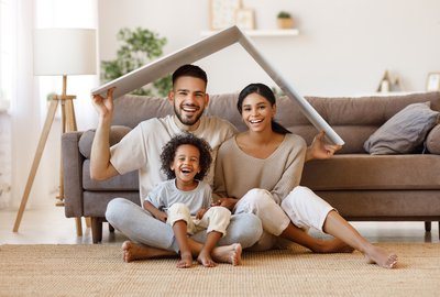 Two adults and a child under a tiny roof in a home.