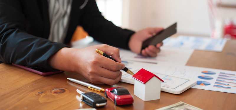 Person using a phone while at a table with a toy car and house and some charts.