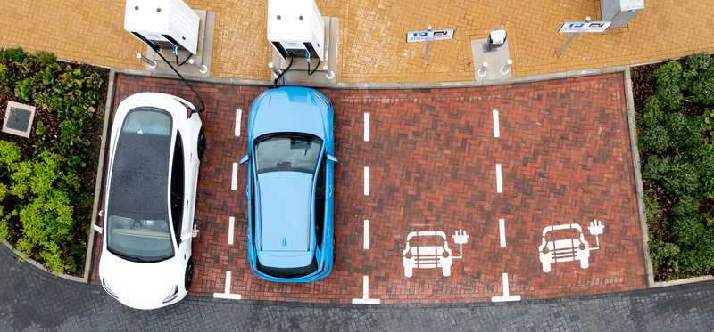 Overhead shot of two electric cars at EV charging stations.