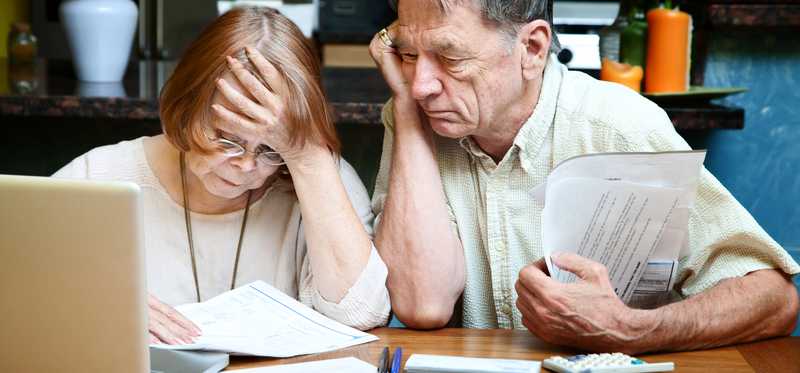 An elderly couple looking through paperwork together.