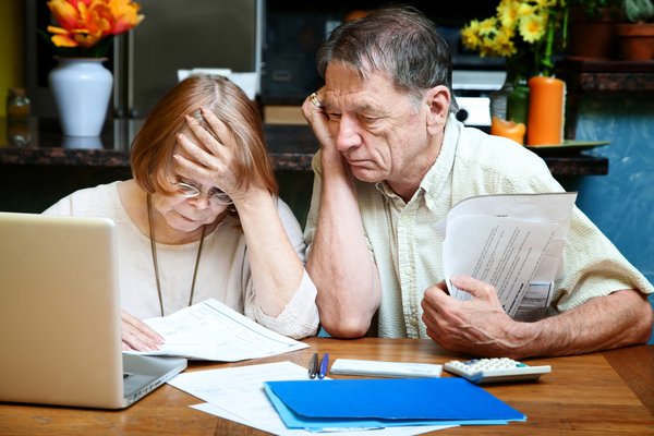 An elderly couple looking through paperwork together.
