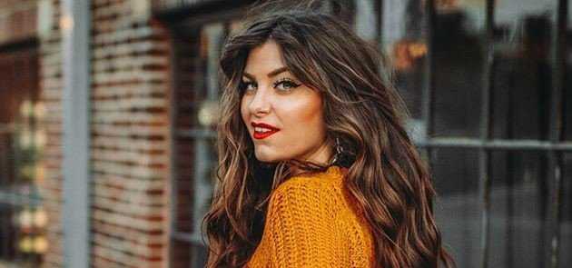 A woman is wearing an orange sweater.