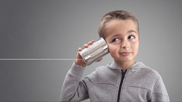 young child listens on one end of an aluminum can string phone