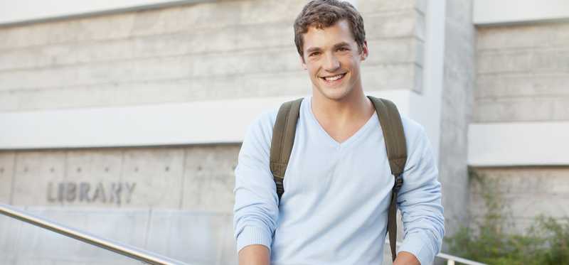 Student standing on steps holding notebooks.