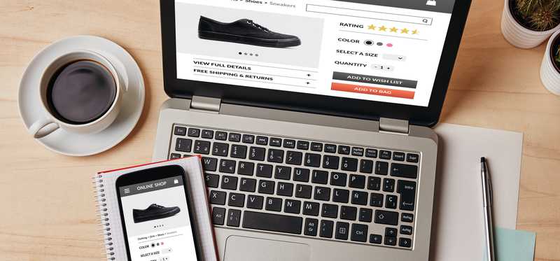 Cell phone and coffee sitting by laptop with shoes for sale being displayed on screen.