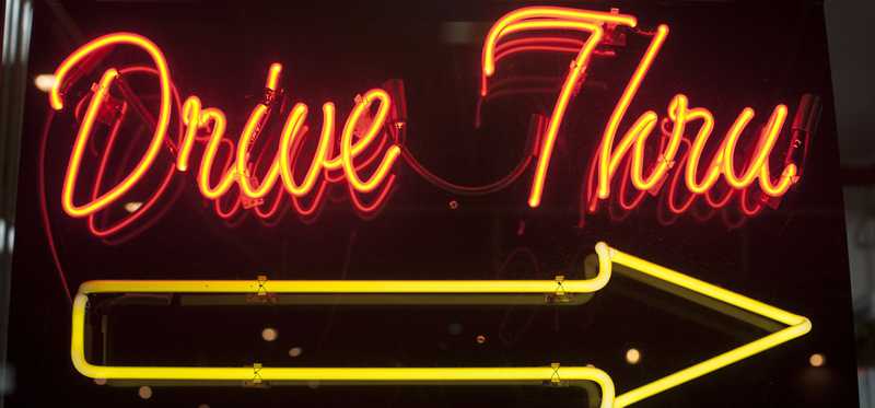 A lit up neon sign reading drive-thru.