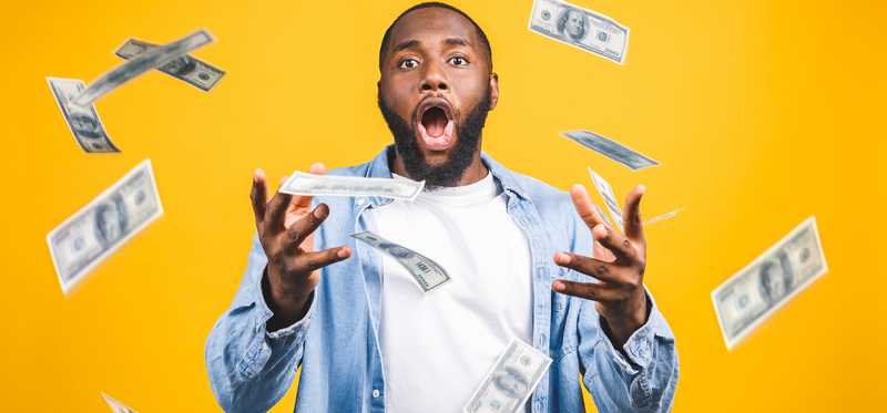 Surprised man in middle of falling hundred dollar bills