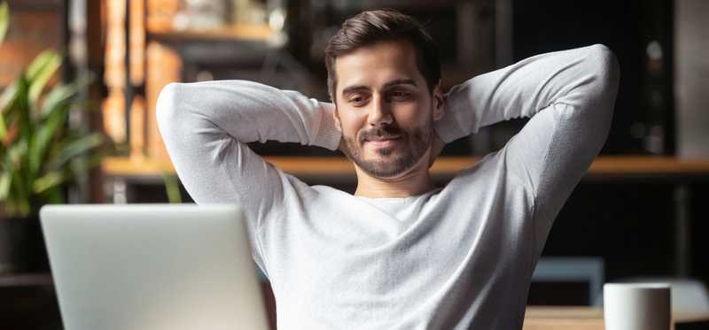 Man leans back with hands behind his head and looking satisfied