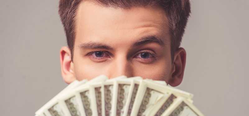 Person holding dollar bills up under their eyes.