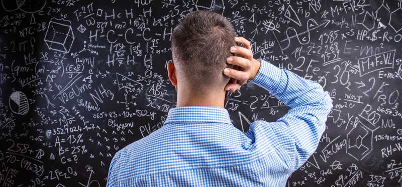 Confused person staring at blackboard with complicated equations.
