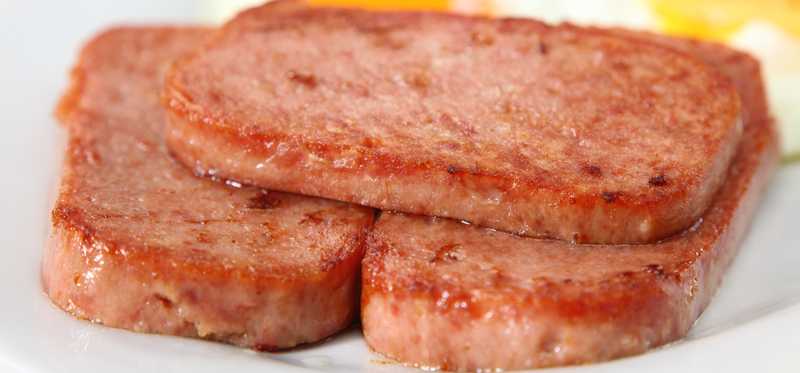 A few slices of cooked Spam on a plate.