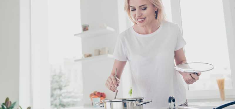 Person stirring a pot on a stove.