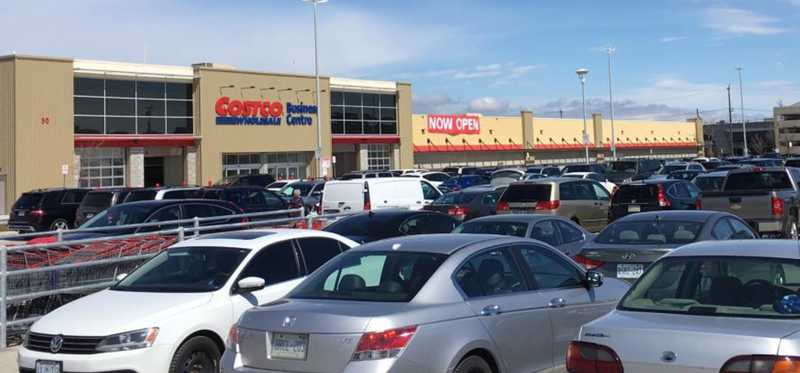 The exterior of a Costco store with many cars in the parking lot.