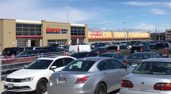 The exterior of a Costco store with many cars in the parking lot.