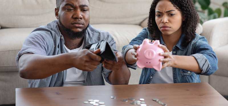 Couple empties piggy bank and wallet on coffee table.