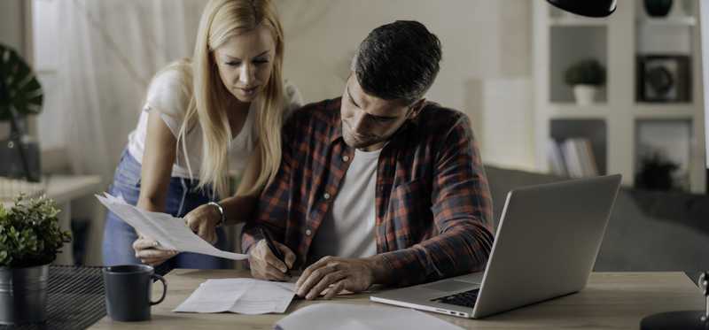 Two people with a laptop and paper forms.
