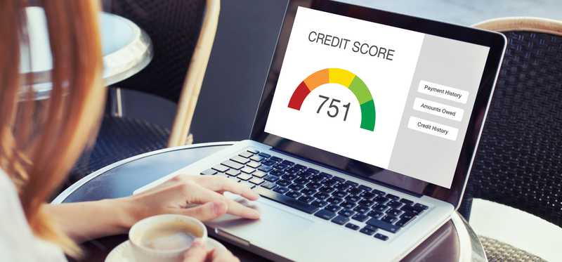 Person with coffee cup and laptop with credit score showing.