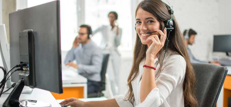 A woman wears a headset as she sits in a call center.