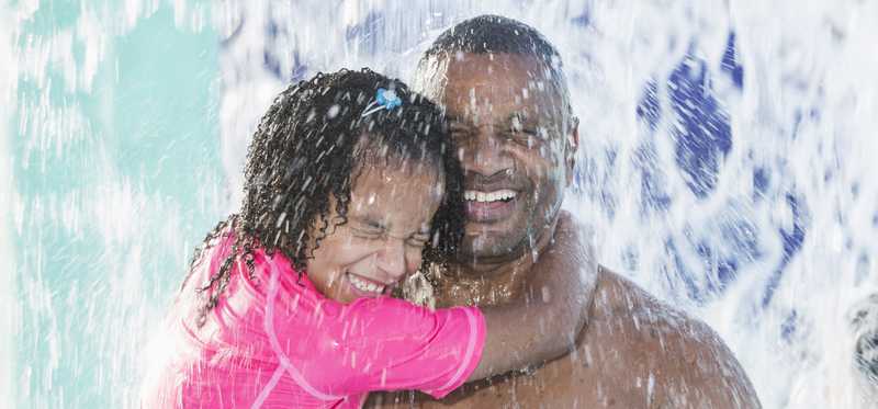 Two people having fun getting drenched at a waterpark.