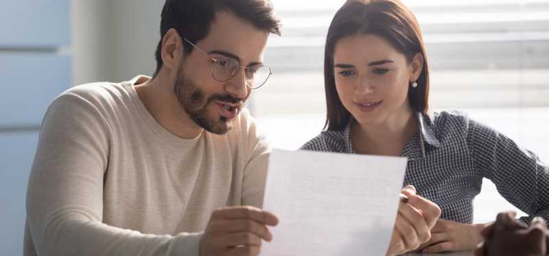 Two people look at document together at a table.