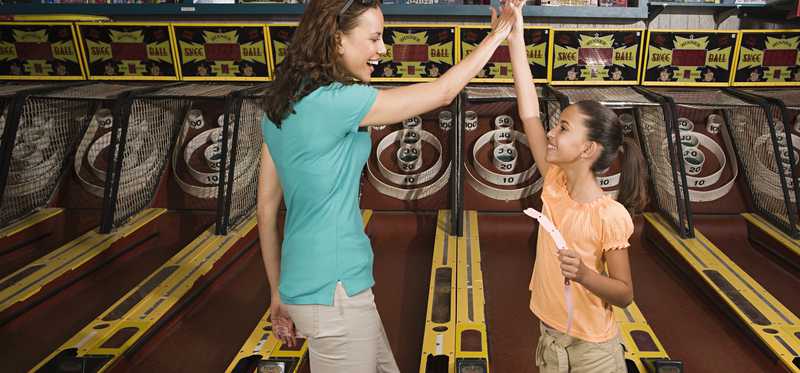Mom and daughter high fave inside arcade.