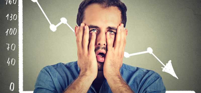 Dejected investor holds his face in his hands.
