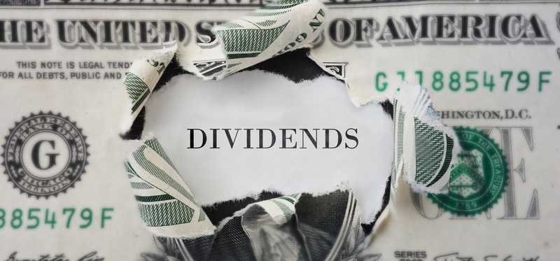 The word Dividends inside a torn-open dollar bill.