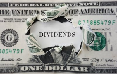 The word Dividends inside torn-open dollar bill.