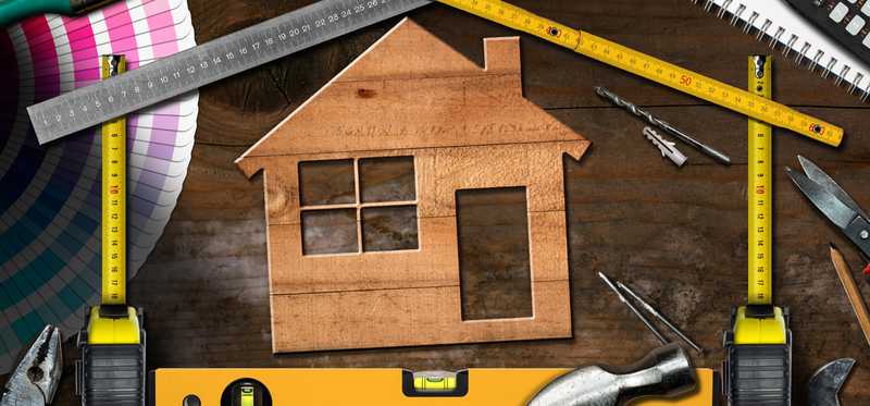 Wooden house cutout surrounded by home improvement tools.