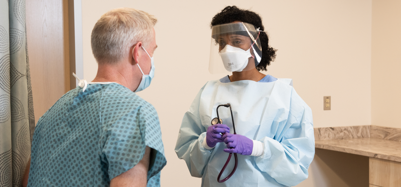 Doctor wearing N95 mask and surgical gown with patient.