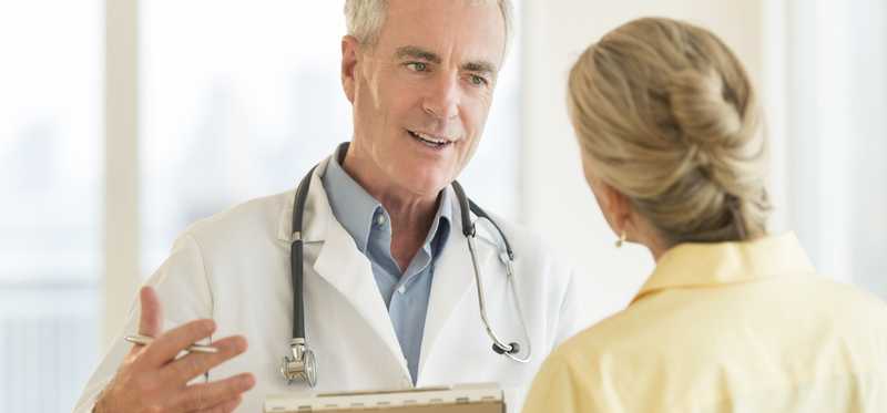 An older male physician speaks with his female patient.