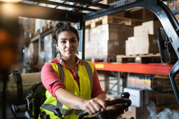 A person driving a forklift in a factory or warehouse.