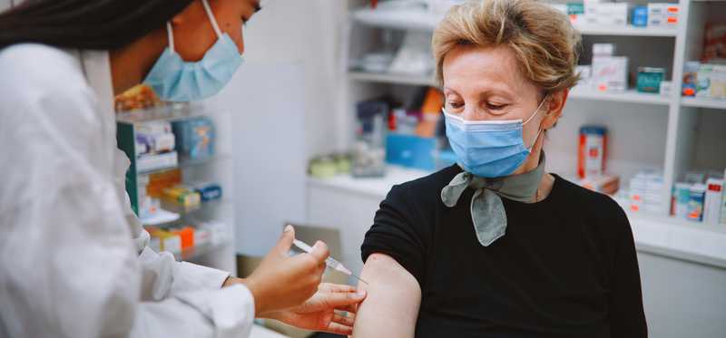 A person giving another person an injection in a drugstore setting.