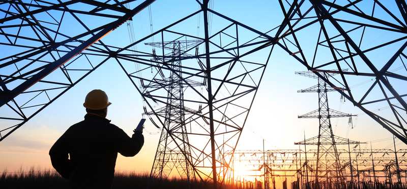 Person underneath big electric towers and lines.