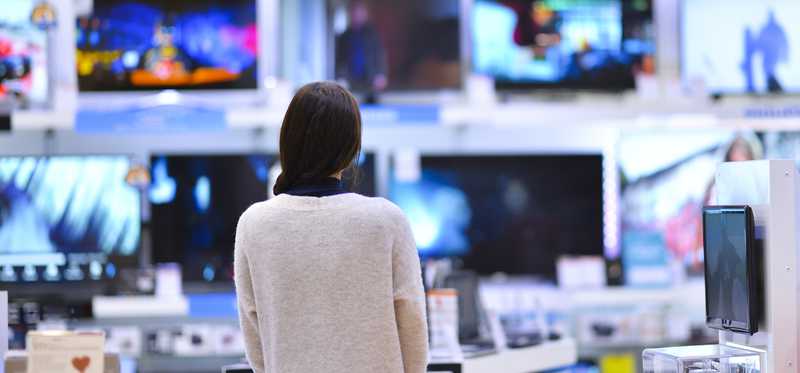 Person looking at many TVs while shopping in an electronics store.