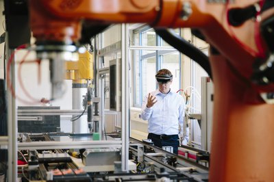 Engineer with a HoloLens placing virtual robotic arm into the production line.jpg