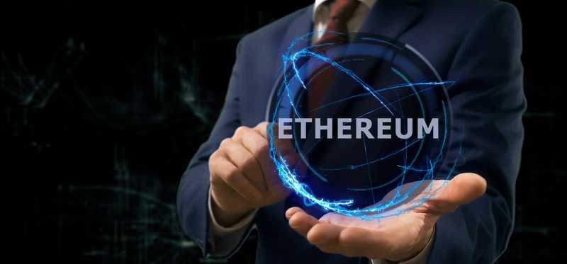 Person with outstretched hand holding digital globe that says Ethereum.