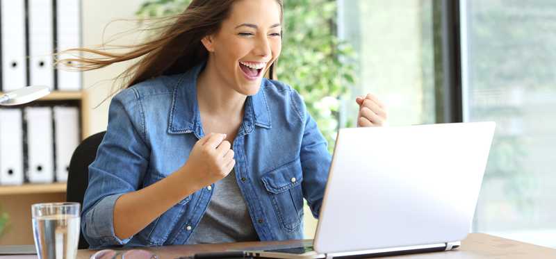 Excited woman at a laptop smiling.