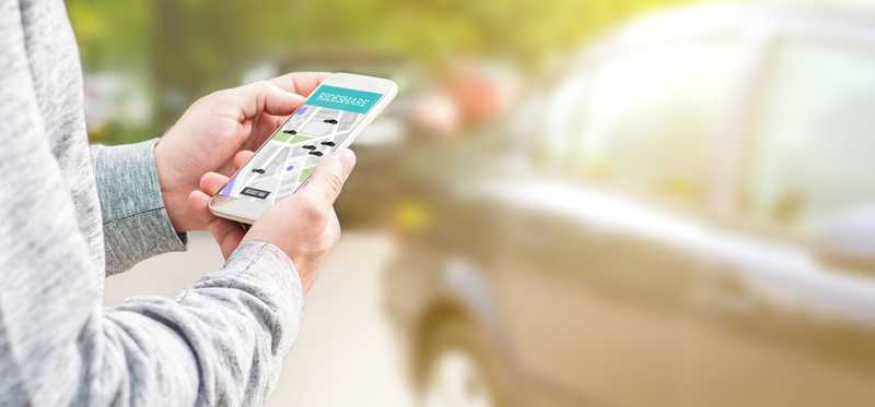 A person uses a ridesharing app on a phone.