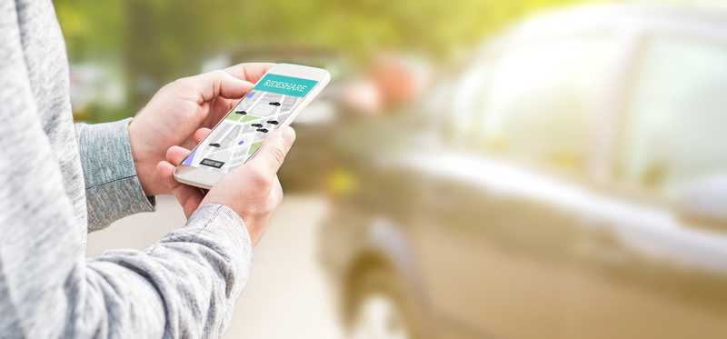 A person uses a phone app to call a ride share