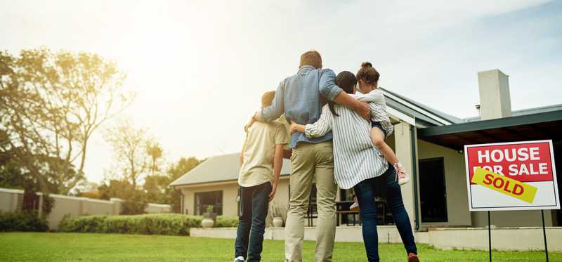 Family embracing and turned around looking at new home