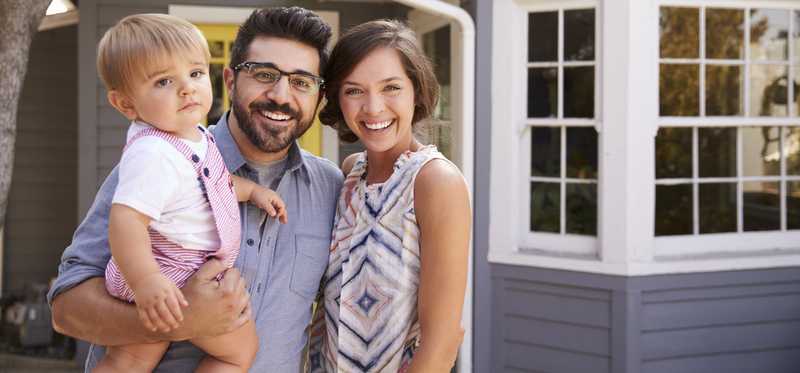 Family smiling in front of their home.