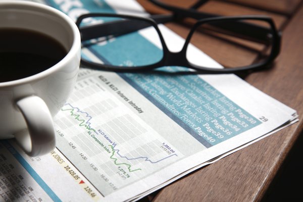 Coffee and eyeglasses sitting on a financial newspaper.