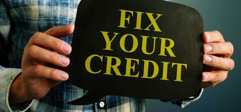 Person holding small chalkboard that says Fix Your Credit.