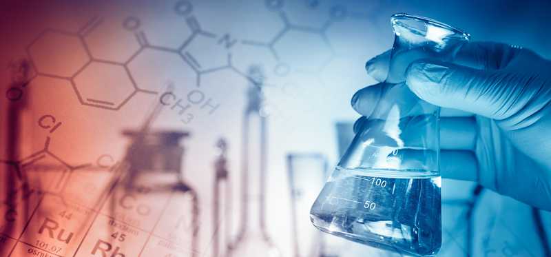 Hand holding flask with periodic table background