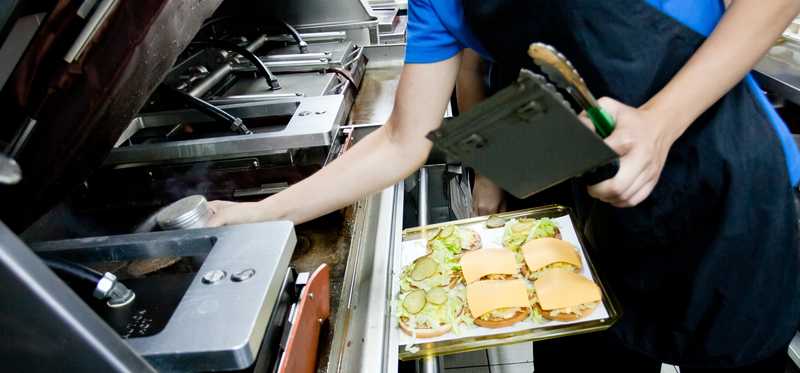 A person at an oven in a fast-food restaurant.