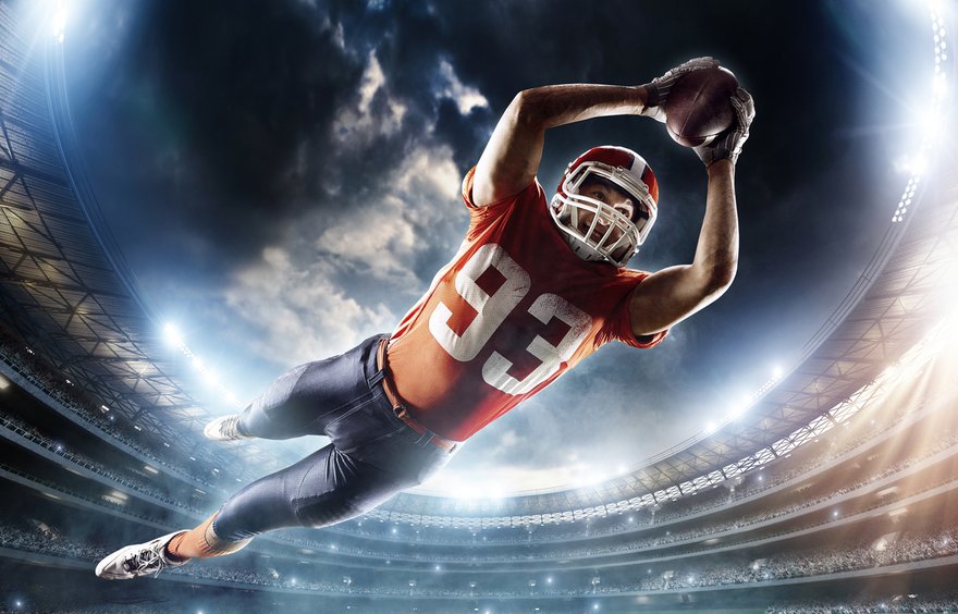 Football player soaring through the air to land a touchdown.
